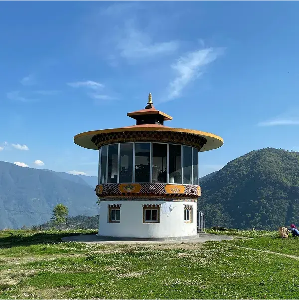 Round pavilion with a tiered roof on a grassy hillside