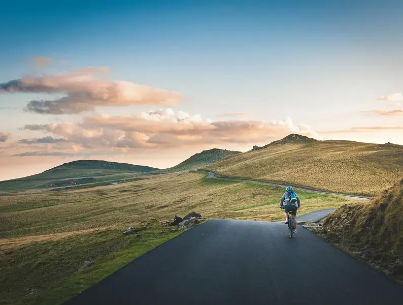 Person walking down a road through open grassland