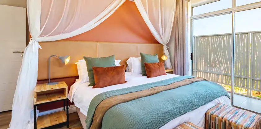 Bedroom at Miombo Mews with a canopy bed and air-conditioning