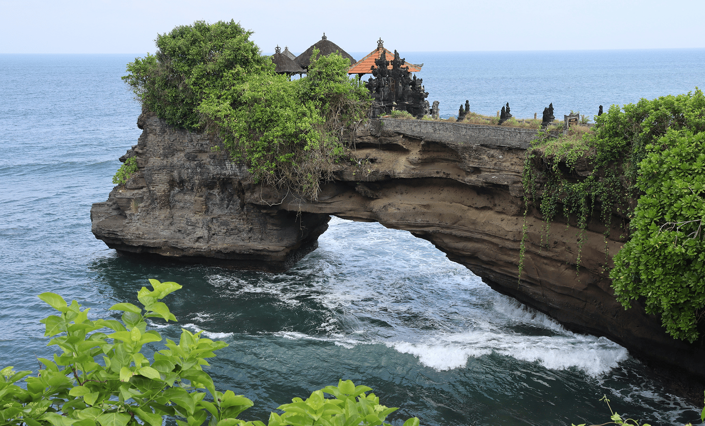Rock arch over the sea with a small temple on top