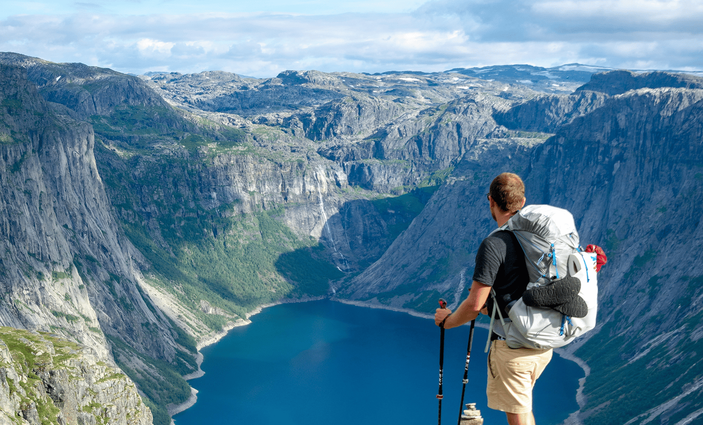 Hiker with a backpack looking over a fjord from a cliff